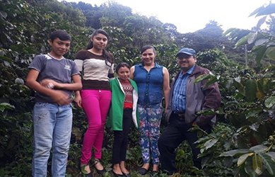 무성한 초록색 커피 나무들로 둘러싸인 커피 농장에서 밝은 표정으로 포즈를 취하고 있는 5인 가족의 모습. 네스프레소의 지속가능한 ESG 경영전략의 핵심인 커피 농가와의 협업과 공급망 지원을 상징하는 이미지.