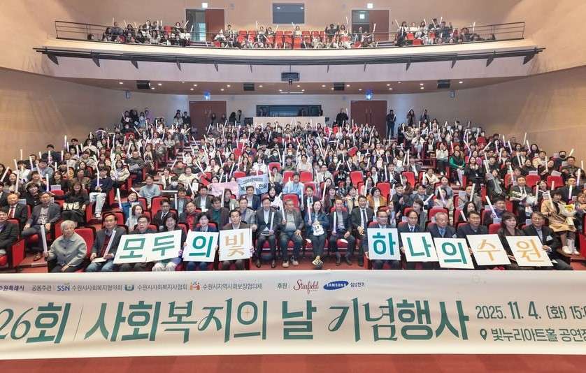 제26회 수원시 사회복지의 날 기념행사에서 수원시사회복지협의회 및 관계자들이 '모두의 빛 하나의 수원' 현수막을 들고 사회적 가치 실증과 성과 중심 운영 전략을 다짐하는 단체 기념사진